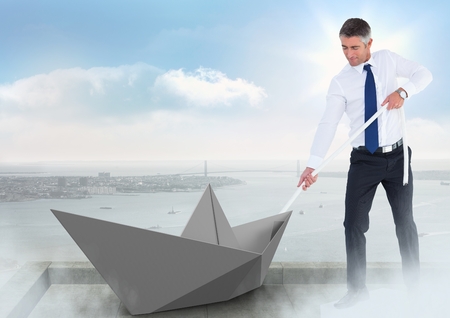 Digital composite of Businessman pulling paper boat with rope in city skyの写真素材