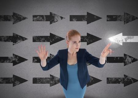 Digital composite of Businesswoman touching glowing arrow in opposite directionの写真素材