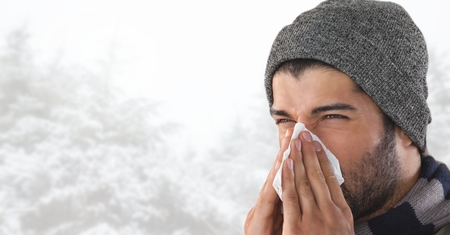 Digital composite of Man blowing his nose in bright snow forestの写真素材