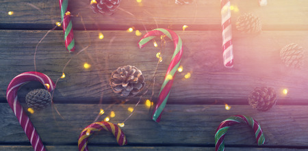 Overhead view of candy canes and pine cones on wooden tableの写真素材