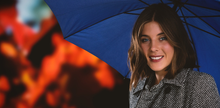 Portrait of woman with blue umbrella against close-up of maple leaves