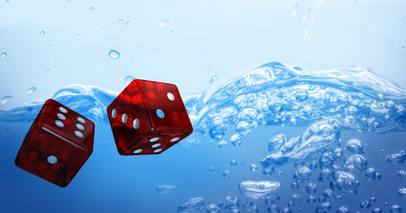 Digital composite 3D image of red dice against close up on blue sparkling waterの写真素材