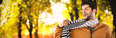 Young man wearing scarf posing against white background against defocused image of trees growing at parkの写真素材