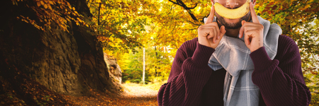 Portrait of man holding banana against country road along trees in the lush forestの写真素材