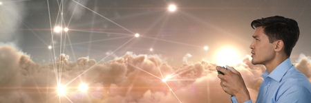 Digital composite of Businessman playing with computer game controller with light connections clouds...
