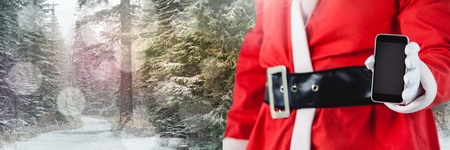 Digital composite of Santa with Winter landscape using tabletの写真素材