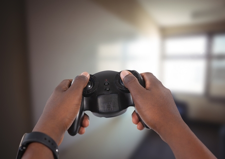 Digital composite of Hands playing with computer game controller with bright blurred background