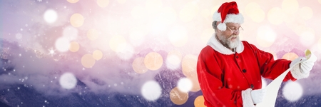 Digital composite of Santa with Winter landscape reading listの写真素材