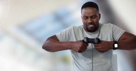 Digital composite of man playing with computer game controller with bright blurred background