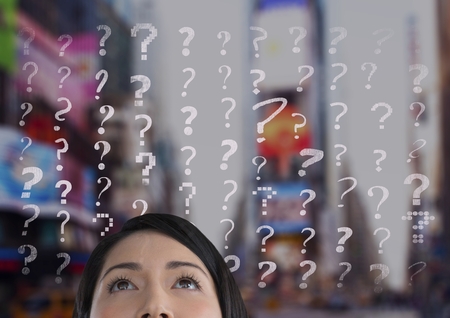 Digital composite of woman looking up at question marksの写真素材