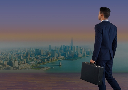 Digital composite of Businessman holding briefcase over cityの写真素材