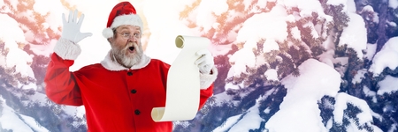 Digital composite of Santa with Winter landscape reading listの写真素材