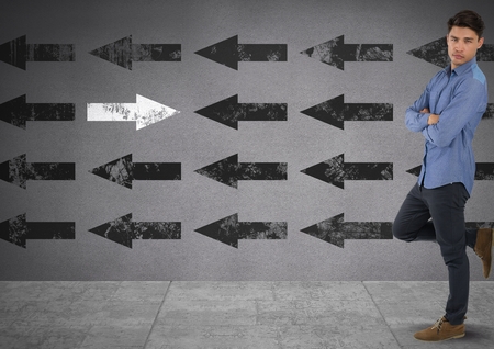 Digital composite of Businessman standing casually with arms folded and arrows in opposite directionsの写真素材