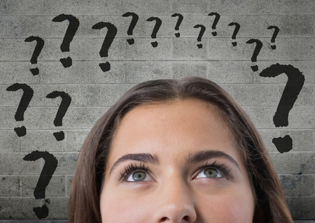 Digital composite of woman looking up at question marksの写真素材