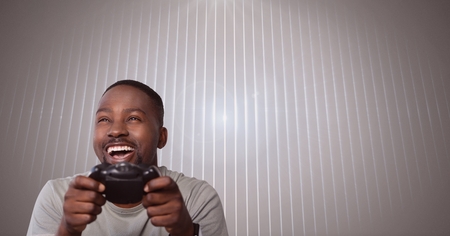 Digital composite of man playing with computer game controller with bright ridged background
