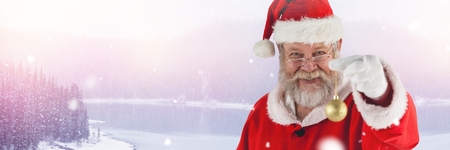 Digital composite of Santa Claus in Winter with Christmas bauble decorationの写真素材