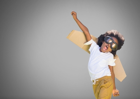 Digital composite of Kid against grey background with cardboard wingsの写真素材