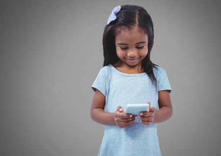 Digital composite of Girl smiling against grey background with phoneの写真素材