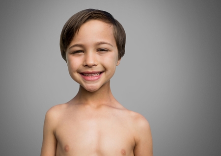 Digital composite of Boy against grey background smiling