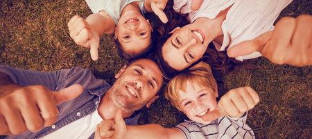Portrait of happy family in park together gesturing thumbs upの写真素材