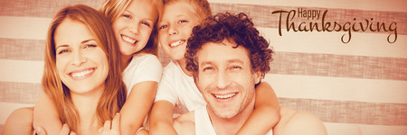 Illustration of happy thanksgiving day text greeting against portrait of happy family on bedの写真素材