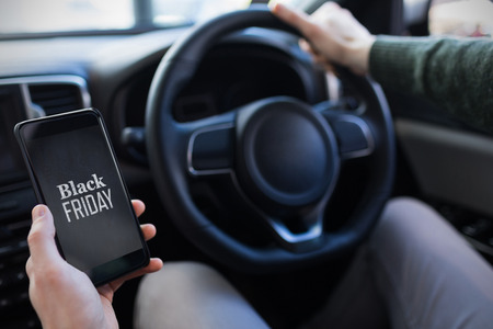 Black friday advert against man looking at gps on his phoneの写真素材