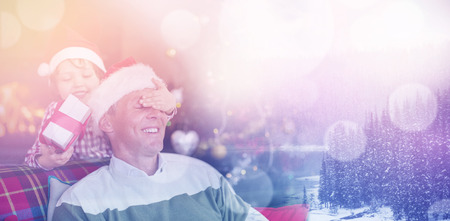 Snow covered pine trees on lakeside against son surprising his father with christmas giftの写真素材