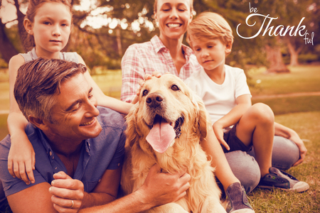 Digital image of happy thanksgiving day text greeting against happy family enjoying with dog at parkの写真素材