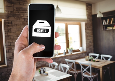 Digital composite of Hand using phone with donate charity box icon