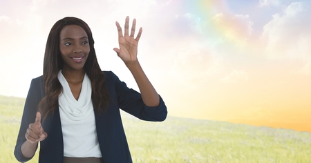Digital composite of Businesswoman touching air in front of meadow cloudsの写真素材