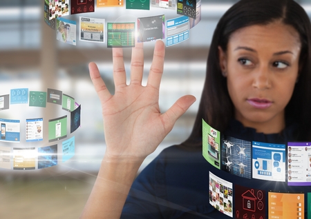 Digital composite of Screens rotating interface and Businesswoman opening hand in front of windows in large hallの写真素材