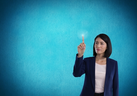 Digital composite of Businesswoman touching air in front of blue backgroundの写真素材