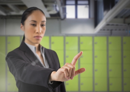 Digital composite of Businesswoman touching air in front of lockersの写真素材