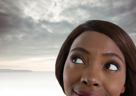 Digital composite of Woman looking up with cloudy backgroundの写真素材