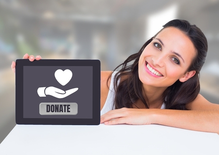 Digital composite of Woman holding tablet with donate button and hand giving heart icon for charity