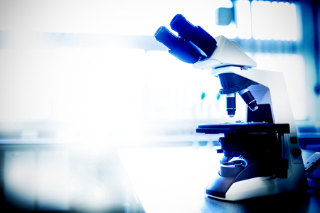 Microscope in laboratory  against empty chairs in modern meeting room