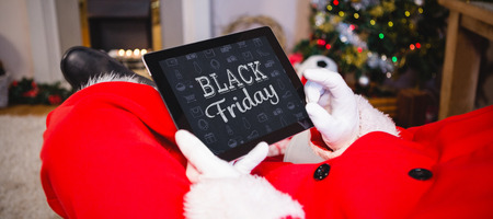 black friday against santa claus sitting and using digital tabletの写真素材
