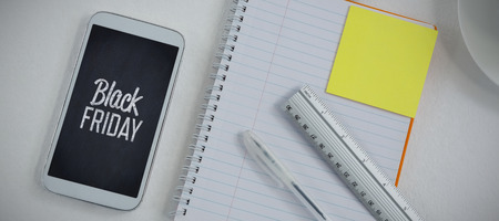 Mobile phone and stationery on white background against black friday advertの写真素材