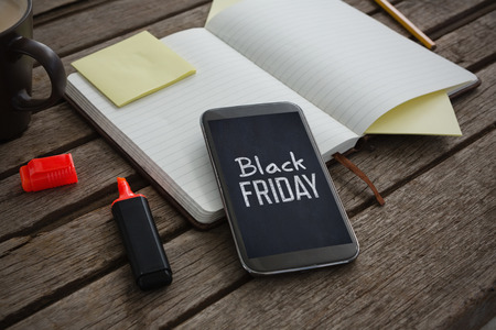 Organizer, coffee, mobile phone and stationery on wooden plank against black fridayの写真素材