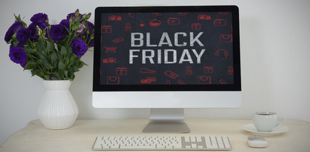 Desktop pc, vase and coffee on table against black friday advertisementの写真素材