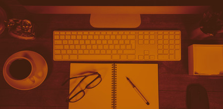 Spiral notepad with black coffee and spectacle on tableの写真素材