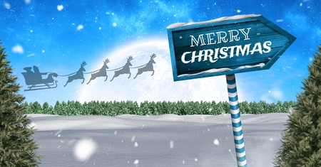 Digital composite of Merry Christmas text on Wooden signpost in Christmas Winter landscape and Santa's sleigh and reindeeの写真素材