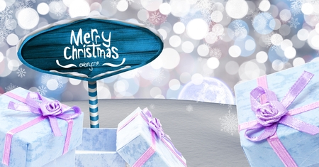 Digital composite of Merry Christmas text and gifts with Wooden signpost in Christmas Winter...