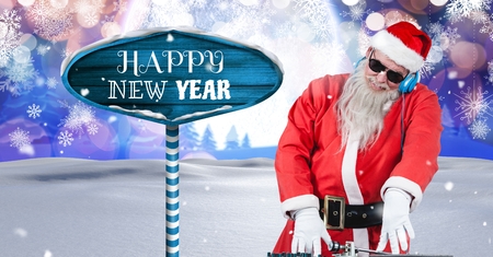 Digital composite of Happy New Year text and Santa DJ with Wooden signpost in Christmas Winter landscapeの写真素材
