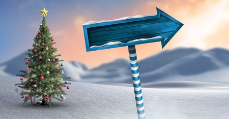 Digital composite of Wooden signpost in Christmas Winter landscape with Christmas treeの写真素材