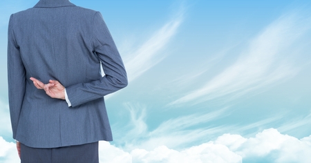 Digital composite of Businesswoman with fingers crossed in skyの写真素材