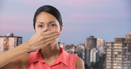 Digital composite of Businesswoman covering mouth with hand in city