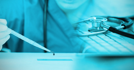 Close-up of keyboard with stethoscope against female doctor experimenting in laboratoryの写真素材