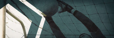 Goalkeeper in red jumping up to save a goal on a clear dayの写真素材