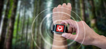 Cropped image of man using watch against digital composite of heart iconの写真素材
